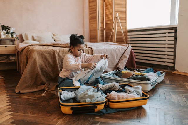 Young child packing a suitcase on the floor